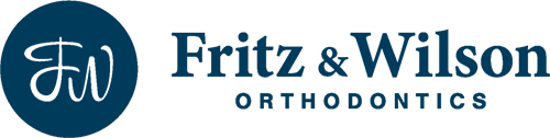 Fritz and Wilson Ortho Logo - Dark blue serif and sans-serif type with FW inside dark blue circle to left
